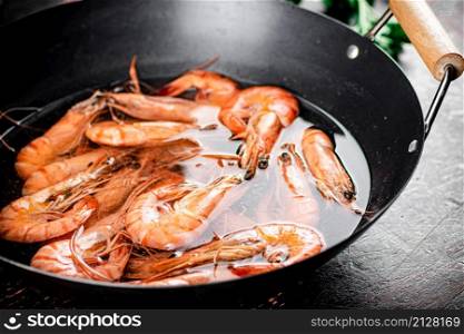 The shrimp are boiled in a pot of water. Against a dark background. High quality photo. The shrimp are boiled in a pot of water.