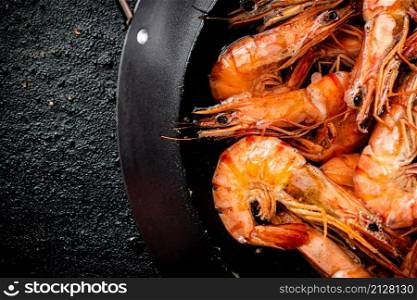 The shrimp are boiled in a saucepan. On a black background. High quality photo. The shrimp are boiled in a saucepan.