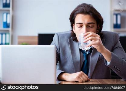 The sick male employee suffering in the office . Sick male employee suffering in the office