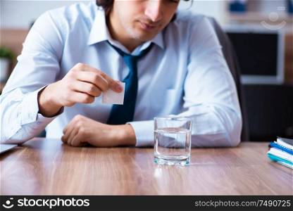 The sick male employee suffering in the office. Sick male employee suffering in the office