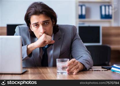 The sick male employee suffering in the office. Sick male employee suffering in the office