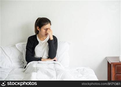 The sick woman had a headache and put her hand on her nose on the bed.