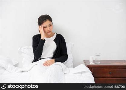 The sick woman had a headache and the hands touched her head on the bed.