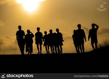 The silhouette of a group of people is celebrating success on the hilltop.