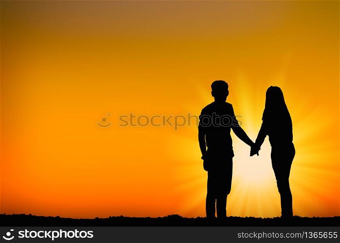 The silhouette of lovers on the top of the mountain During sunset time