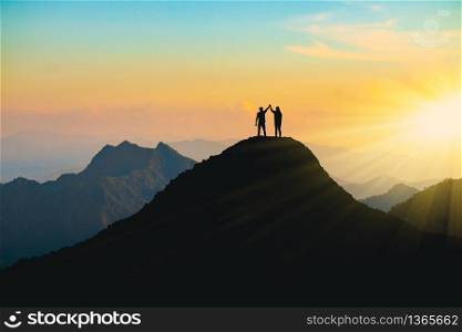 The silhouette of lovers on the top of the mountain During sunset time