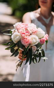 The silhouette of the bride holding a bouquet of delicate roses in her hand.. A large bouquet of white and pink roses in the hands of the bride 3943.