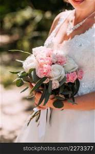 The silhouette of the bride holding a bouquet of delicate roses in her hand.. A large bouquet of white and pink roses in the hands of the bride 3945.