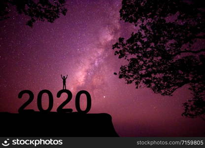 The silhouette of the child standing on the numbers happy new year 2020 with the milky way in the night sky.
