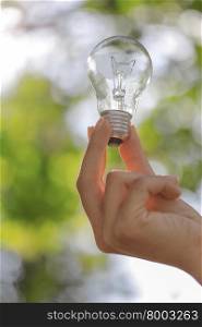 The single light bulb on the hand with natural background.