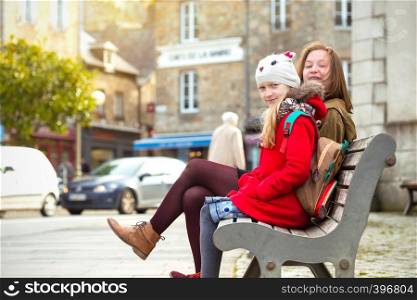 the sisters are sitting on the bench in the famous city of Dinan. France.