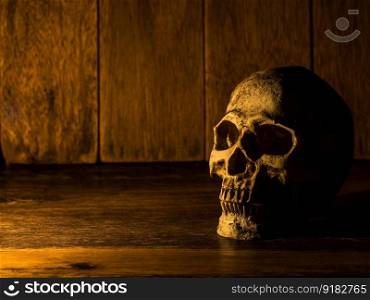 The skull is placed on a wooden table. The background is a wooden plate and light from the candle to the skull.