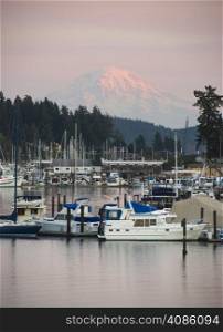 The sleepy harbor of the town of Gig Harbor with Mt Rainier catching the light from sunset in the background