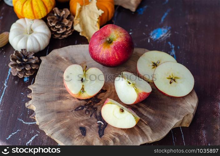 The sliced and whole apples, mini pumpkins, autumn concept on wooden table