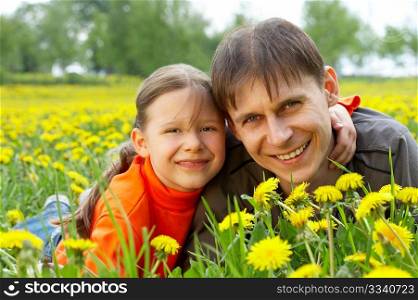 The small daughter and the father in embraces lay on a lawn