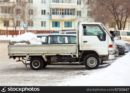 The small truck of white color with snow in a body