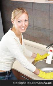 The smiling blonde is engaged in kitchen cleaning. Cleaning