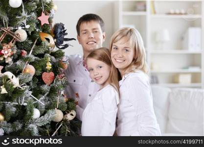 The smiling family of three people close to the spruce