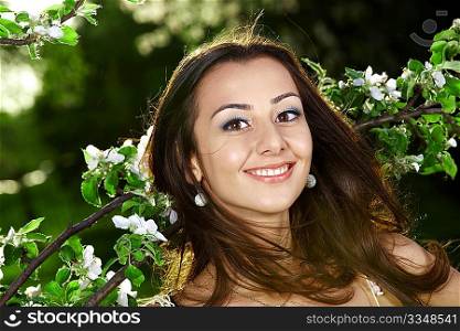 The smiling nice girl in greens of trees