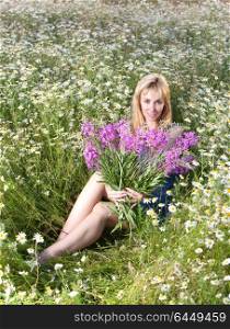 The smiling young woman with bunch of willowherb flower in the field