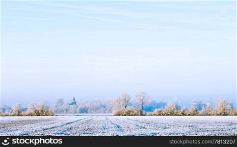 The soft, sun-lit polders and view on the church of Ellewoutsdijk, Zeeland, The Netherlands on a cold, hoarfrosted morning