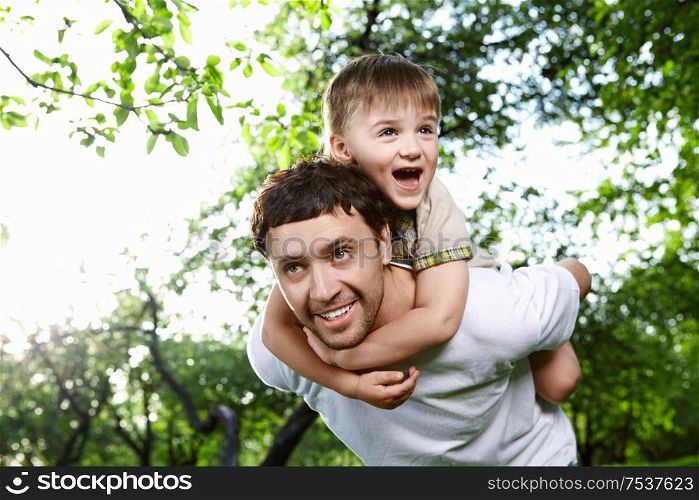 The son embraces the daddy for a neck against the sky and foliage of trees