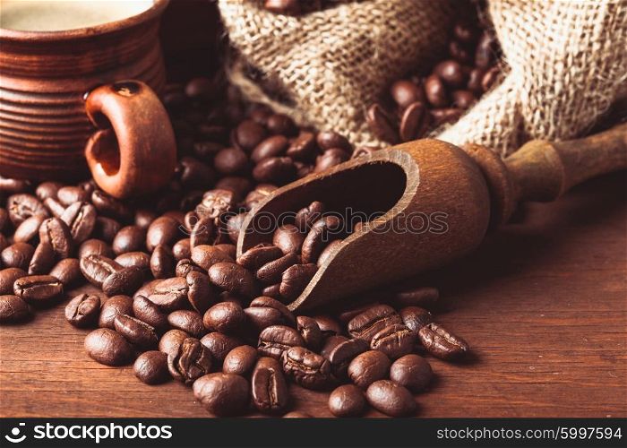 The spilled beans on the table and wooden scoop. Coffe beans close up