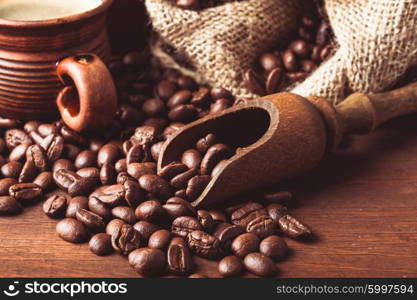 The spilled beans on the table and wooden scoop. Coffe beans close up