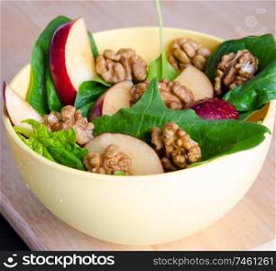 The spinach salad with nuts and apples served on table. Spinach salad with nuts and apples served on table