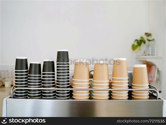 The stack of new take away coffee cups on espresso machine in the minimal cafe or restaurant with copy space, food and drink business