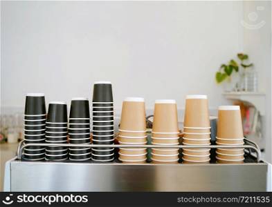 The stack of new take away coffee cups on espresso machine in the minimal cafe or restaurant with copy space, food and drink business