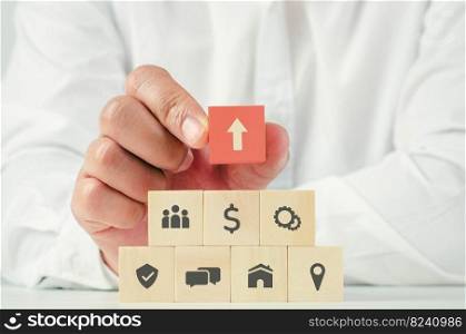 The start of a businessman who picks up a wooden block, the icon of a red rocket is unique. In the new concept of startup, wooden blocks are arranged in a pyramid shape.