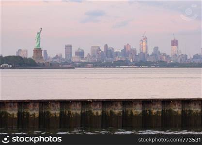 The Statue of Liberty after sunset with Brooklyn New York in the background