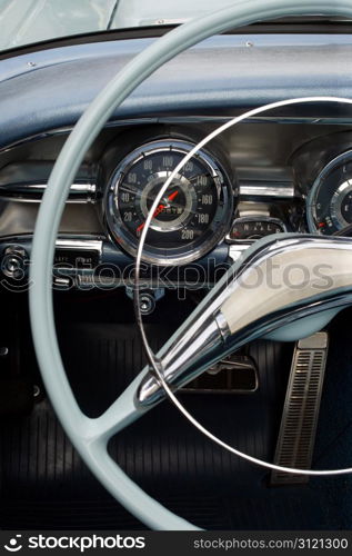 The steering wheel and dashboard of an antique classic car.