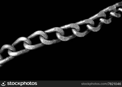 The stell links of a tire chain stretched out diagonally across a tire. Isolated to a black background for contrast.