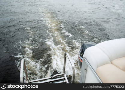 the stern of a motor boat with a bubbling trail of river water