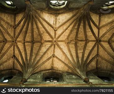 The stone ceiling over the nave of St. Giles Cathedral in Edinburgh, Scotland is criss-crossed with stone work to support the roof. With details illuminated by window light, the atmosphere is quite warm on the inside.