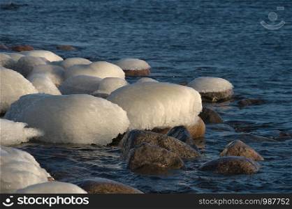 The stones at seaside are breaking open from a sea ice rind and melting in the spring sun like hatching eggs