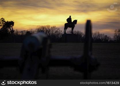 The Stonewall Jackson Memorial silhoutte against a yellow and orange sunset at the Manassas Battlefield Park in Manassas, Virginia