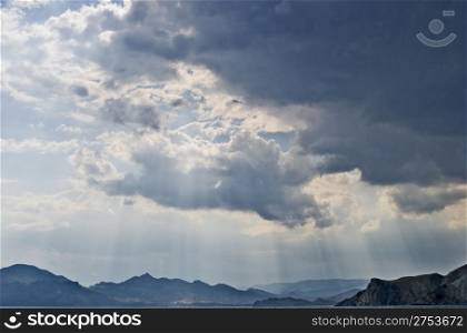 The storm sky above ocean on a background of picturesque mountains