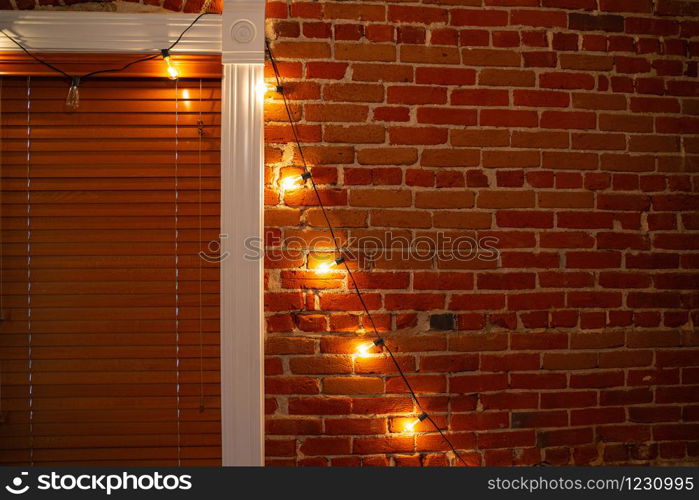 The string of vintage lights bulbs inside at night, lights on a brick wall background, selective focus. Lights bulbs inside