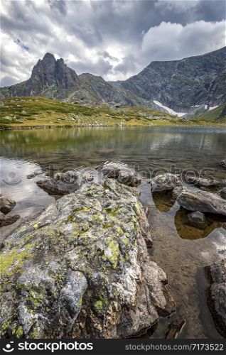 the stunning landscape on the mountain lake with a big rock. Vertical view