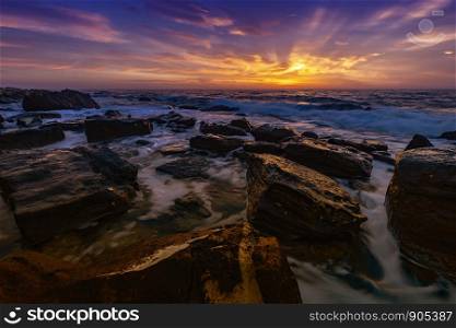The stunning seascape with the colorful sky and last rays at the rocky coastline of the Black Sea