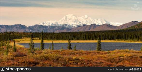 The sun finally rises but stays low in the sky hitting Mount McKinley and the Denali range on a long summer day in Alaska