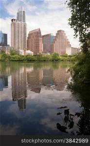 The sun is setting on buildings reflected in the Colorado River as it meanders through Austin, Texas.