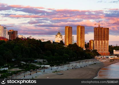 The sun sets over the Amur river. Buildings of the city of Khabarovsk in Golden pink. There are beautiful clouds in the sky.. Sunset over the city of Khabarovsk and the river Amur.