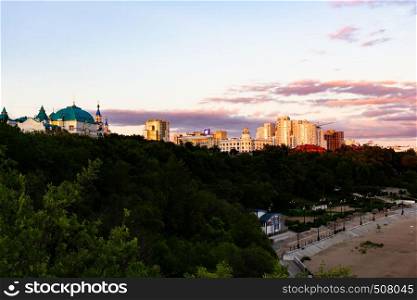 The sun sets over the Amur river. Buildings of the city of Khabarovsk in Golden pink. There are beautiful clouds in the sky.. Sunset over the city of Khabarovsk and the river Amur.