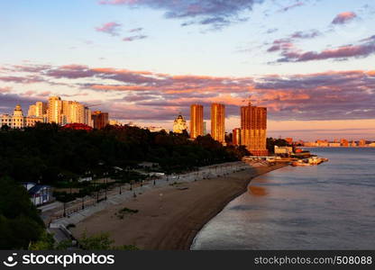 The sun sets over the Amur river. Buildings of the city of Khabarovsk in Golden pink. There are beautiful clouds in the sky.. Sunset over the city of Khabarovsk and the river Amur.