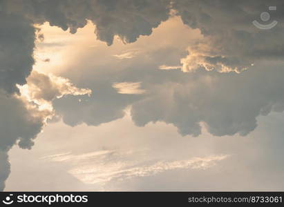 The sun shines through the clouds in the evening sky with dramatic light. The shape of the clouds evokes imagination and creativity, They can be used as wallpaper. Copy space, Selective focus.