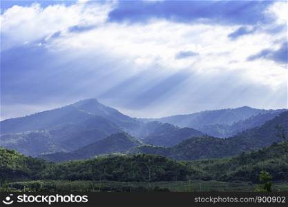 The sun shining through the clouds to the trees on the mountain at Suan phueng of Ratchaburi in Thailand.